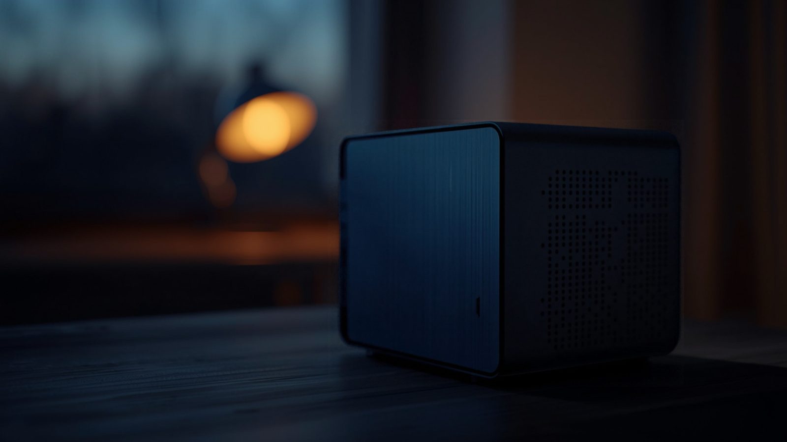 A small computer tower with glowing blue indicator lights on a desk in warm evening light